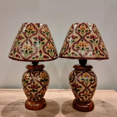 A set of traditional table lamps with hand-painted floral camel skin shades and matching carved bases.