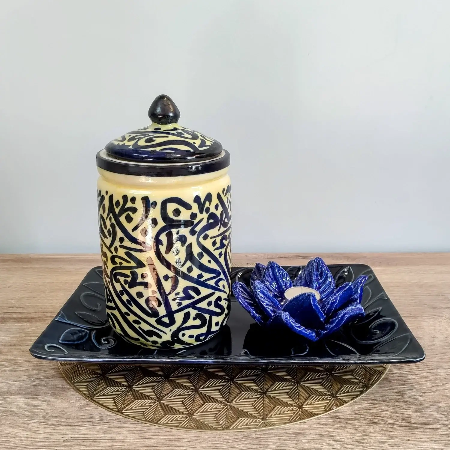 Handcrafted pale-yellow ceramic jars featuring intricate blue Arabic calligraphy, topped with matching lids — available in small, medium, and large sizes.