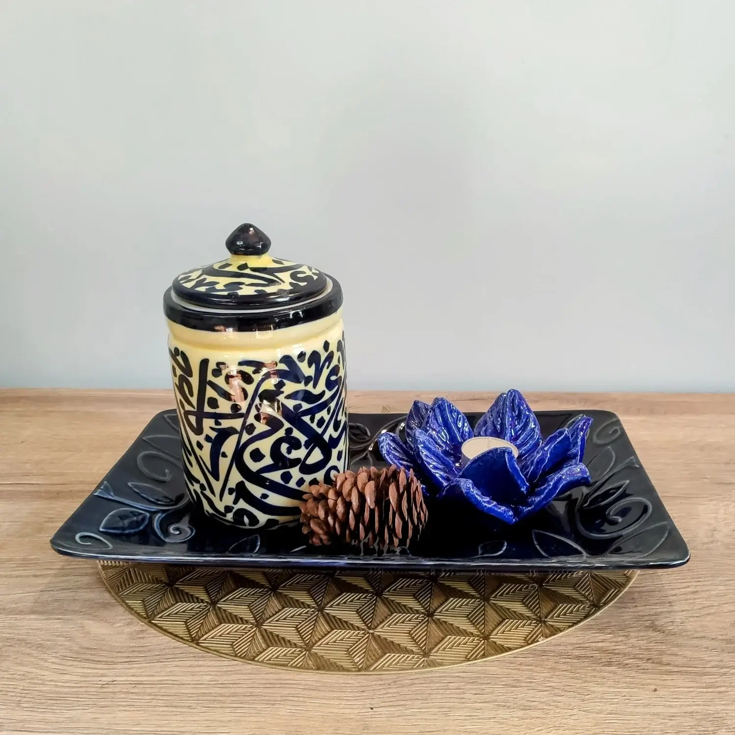 Handcrafted pale-yellow ceramic jars featuring intricate blue Arabic calligraphy, topped with matching lids — available in small, medium, and large sizes.