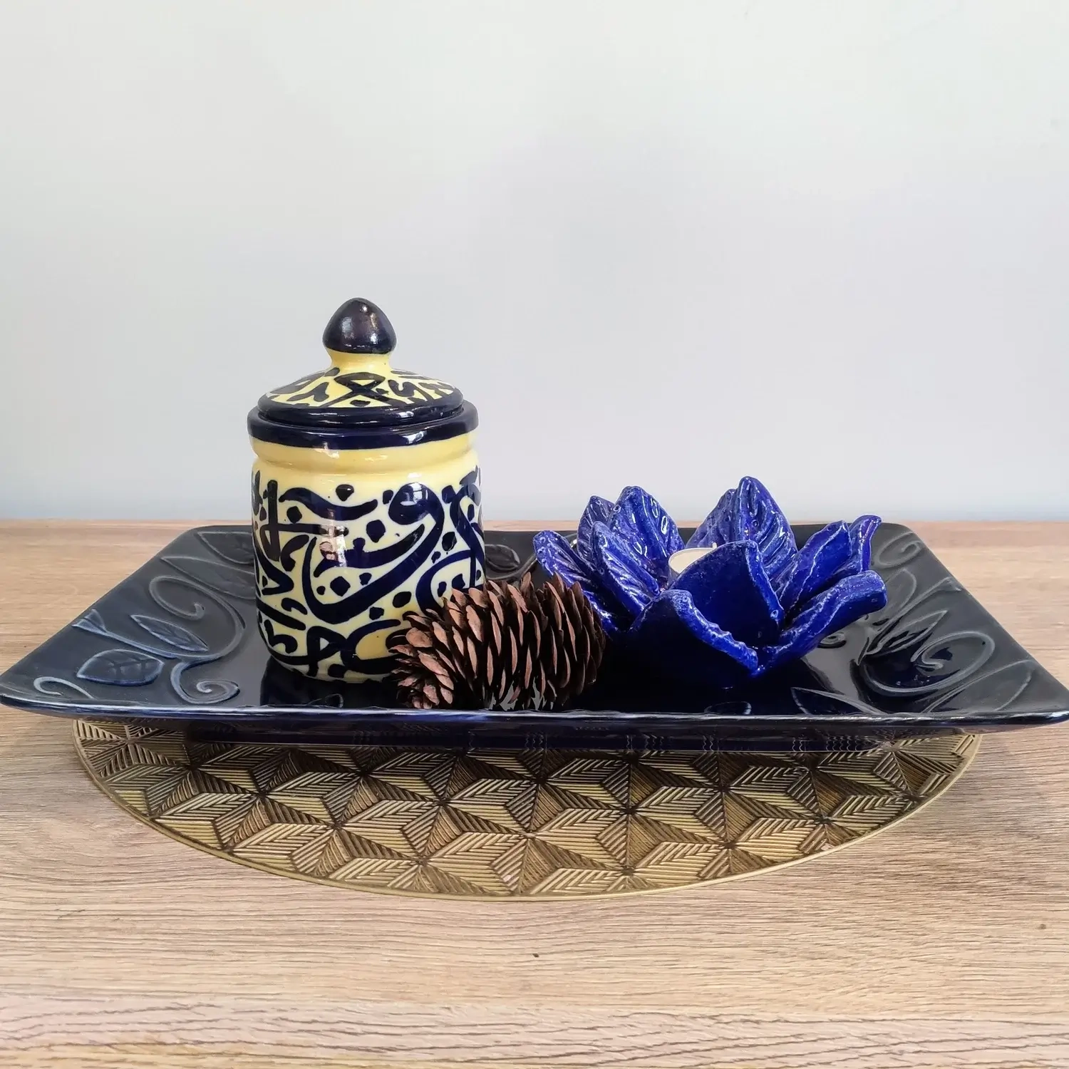 Handcrafted pale-yellow ceramic jars featuring intricate blue Arabic calligraphy, topped with matching lids — available in small, medium, and large sizes.