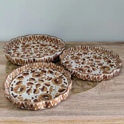 Set of three brown Multani pie dish with floral patterns, displayed on a wooden surface.