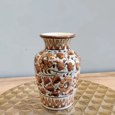 Brown Multani pottery vase with floral patterns, displayed on a gold geometric-patterned mat.