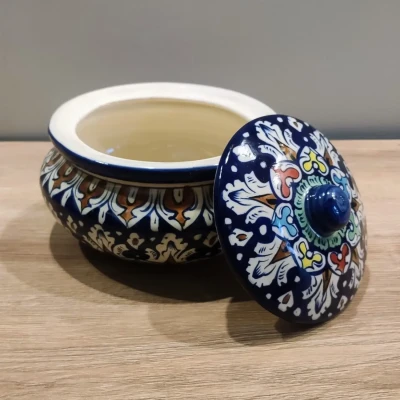 Multicolored Multani pottery handi with a floral-patterned lid, displayed on a wooden surface.