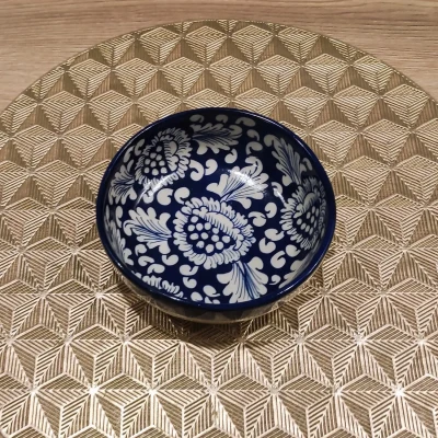 Blue Multani Soup bowl with white floral motifs, displayed on a gold geometric-patterned mat.