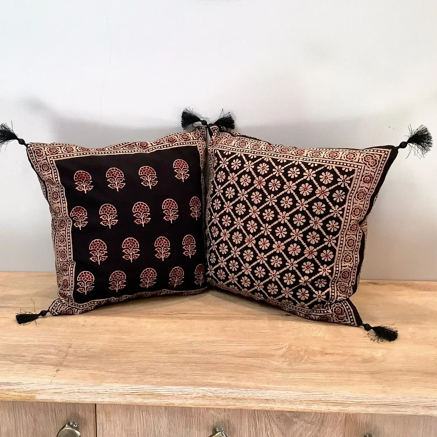 Double-sided Ajrak cushion cover showing floral booti pattern on one side and geometric floral design on the other.