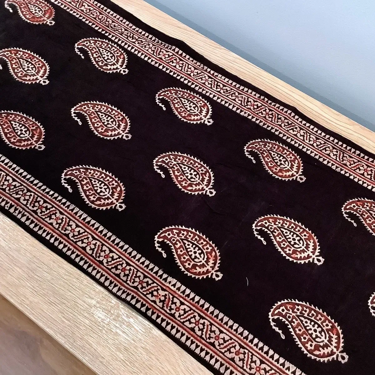 Full view of black block print table runner featuring traditional paisley (Keri) design and tassels.