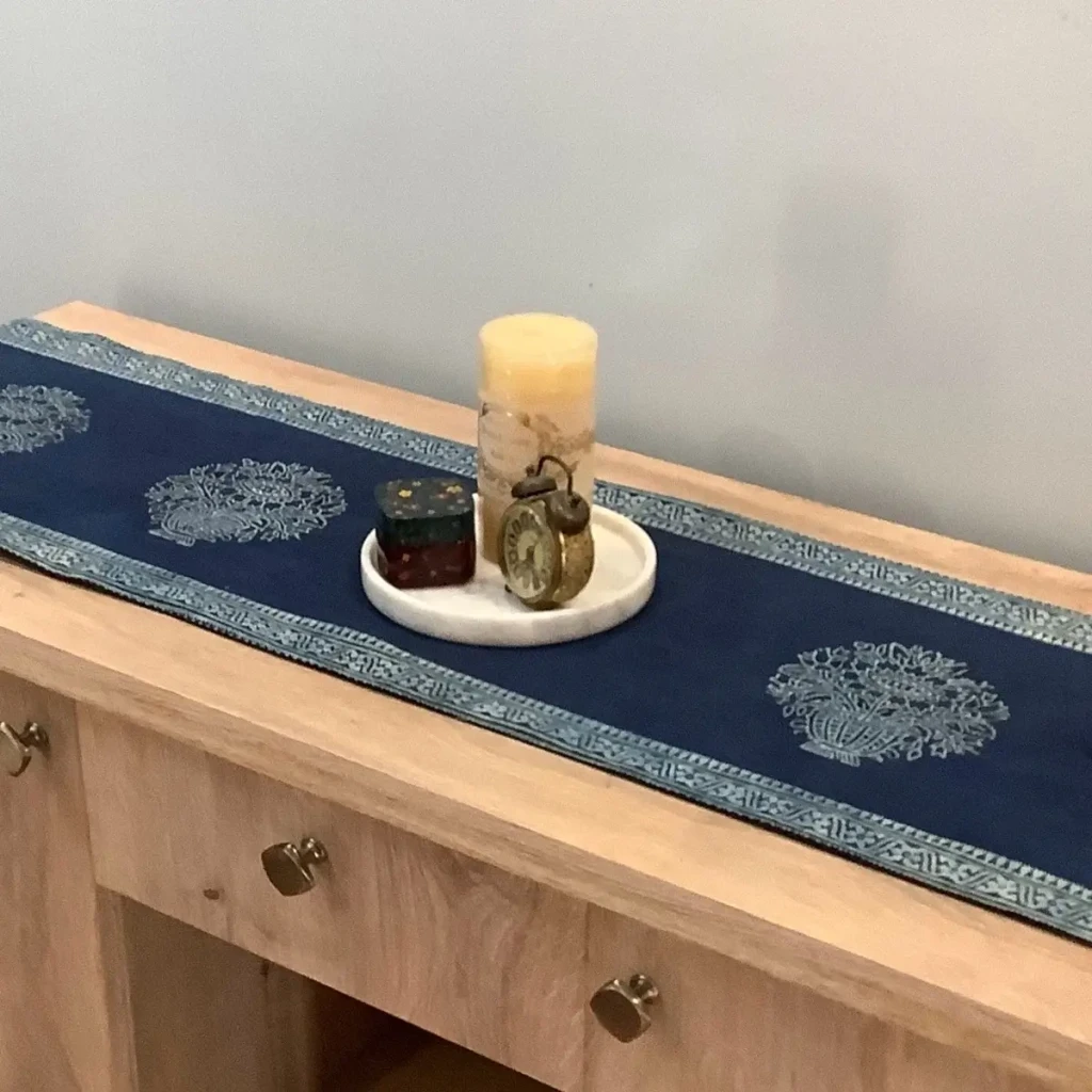 Blue Ajrak block print table runner with floral motifs displayed on a wooden console.