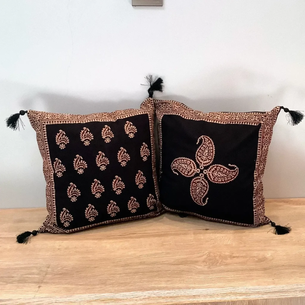 Double-sided Ajrak cushion cover showing repeating Keri booti pattern on one side and a central paisley motif on the other.