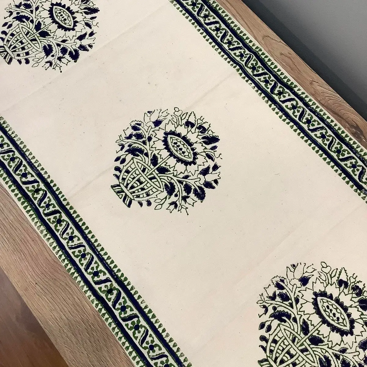 Close-up of green and blue floral medallion block print table runner with traditional bordered detailing.