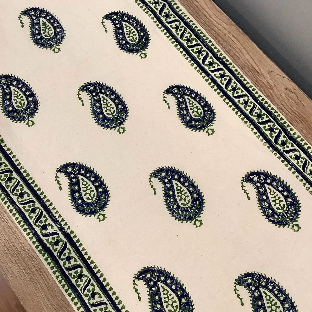 Full view of green and blue Keri patterned block print table runner with traditional borders and tassels.