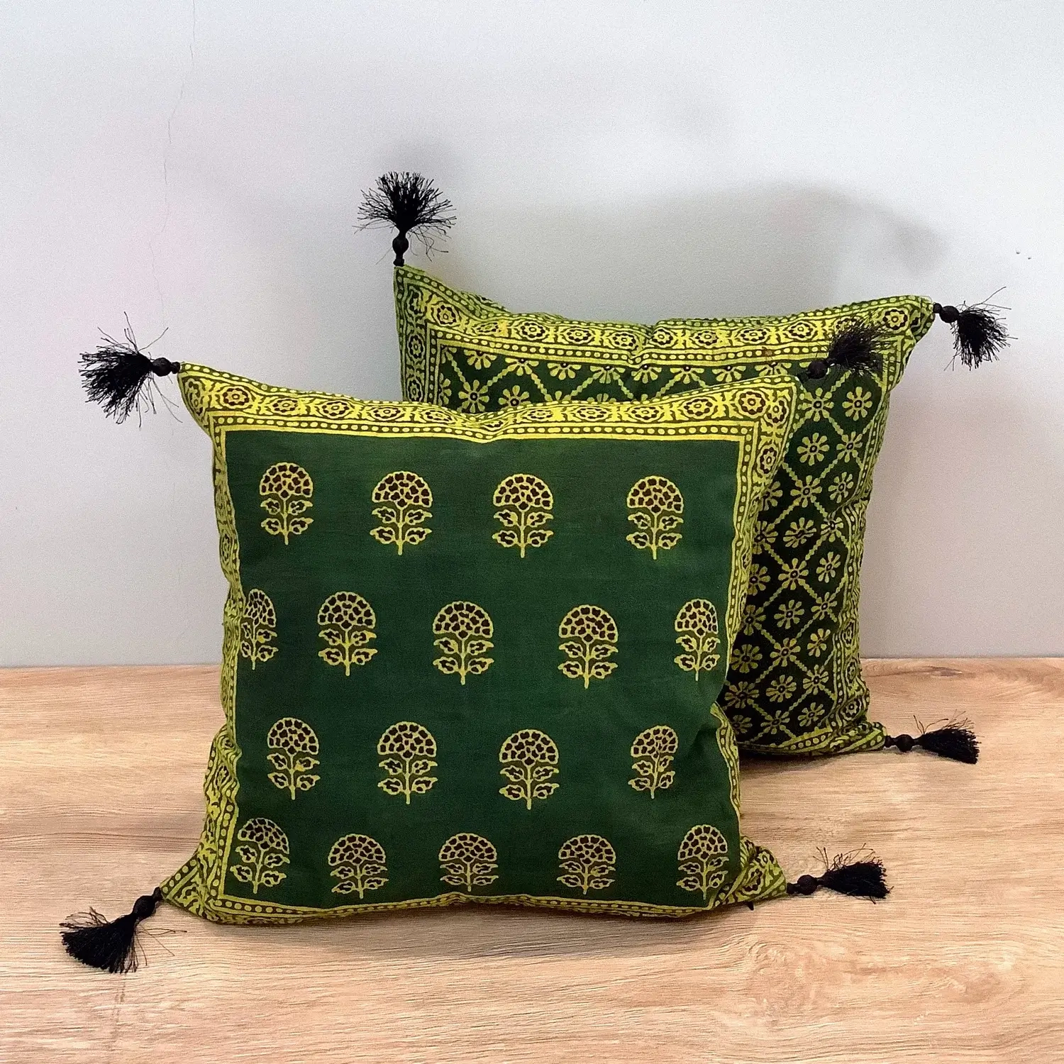 Ajrak block print green floral booti double-sided cushion covers with tassels displayed on a wooden surface.