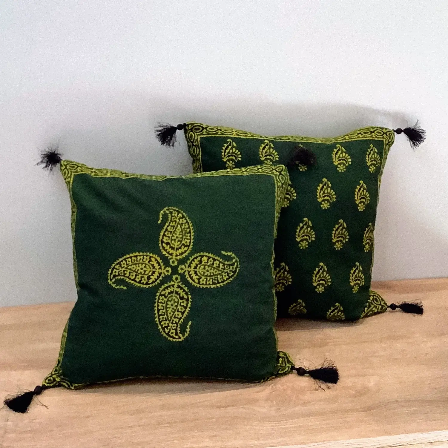 Ajrak block print green keri motif double-sided cushion covers with tassels placed on a wooden surface.