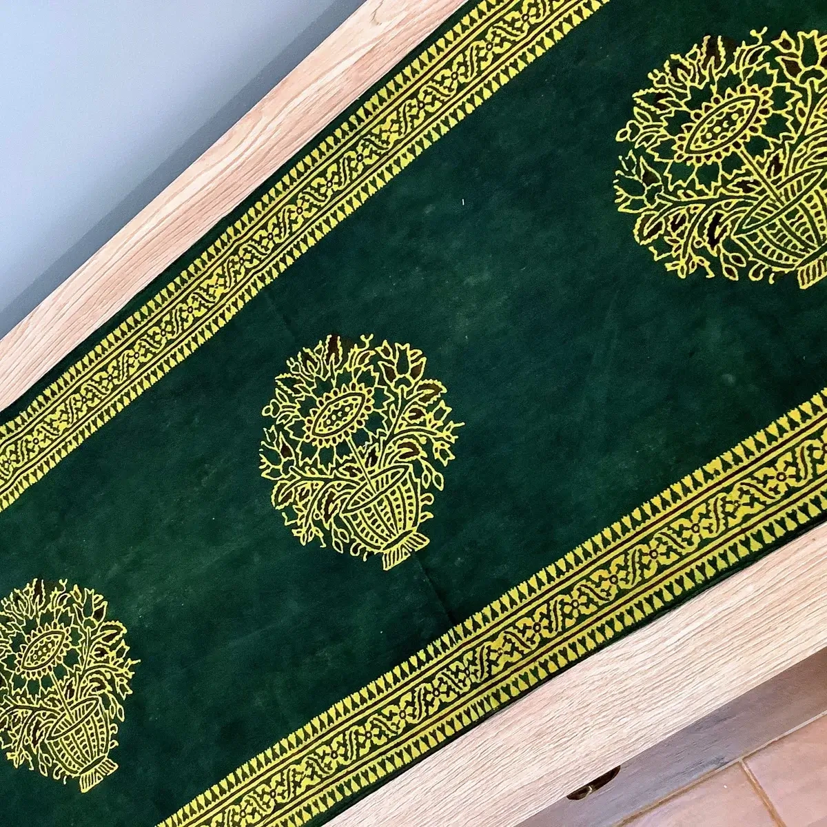 Full view of green floral Ajrak table runner with decorative borders and tassels.