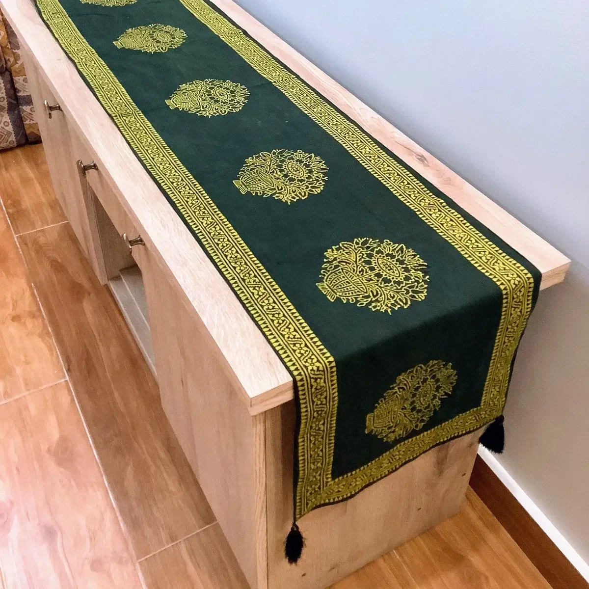 Green Ajrak block print table runner with floral motifs and traditional borders displayed on a wooden console.