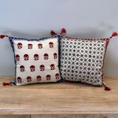 Double-sided Ajrak cushion cover featuring red floral booti motifs on one side and a blue geometric floral pattern on the other.