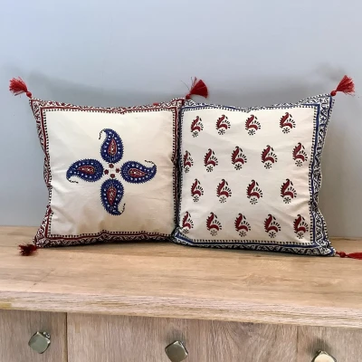 Double-sided Ajrak cushion cover featuring a central red and blue keri motif on one side and repeating keri booti pattern on the other.