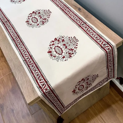 Ajrak and block print off-white table runner with red floral motifs displayed on a wooden console.