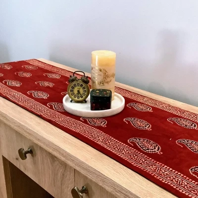 Red Ajrak block print table runner with Keri booti motifs styled on a wooden console table.
