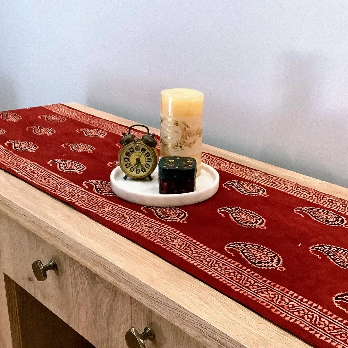 Red Ajrak block print table runner with Keri booti motifs styled on a wooden console table.