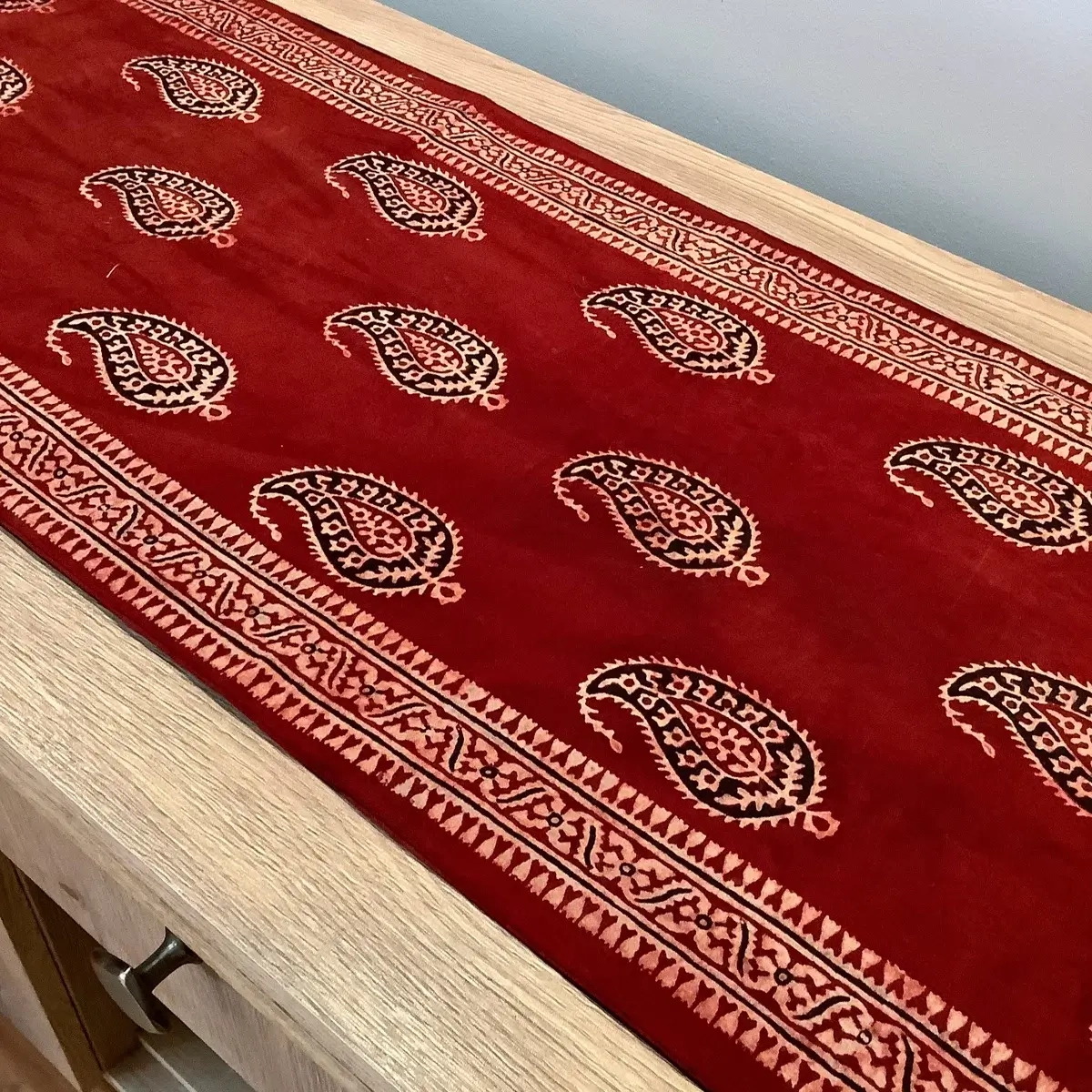 Close-up of red Keri booti Ajrak table runner showing paisley pattern and detailed border.